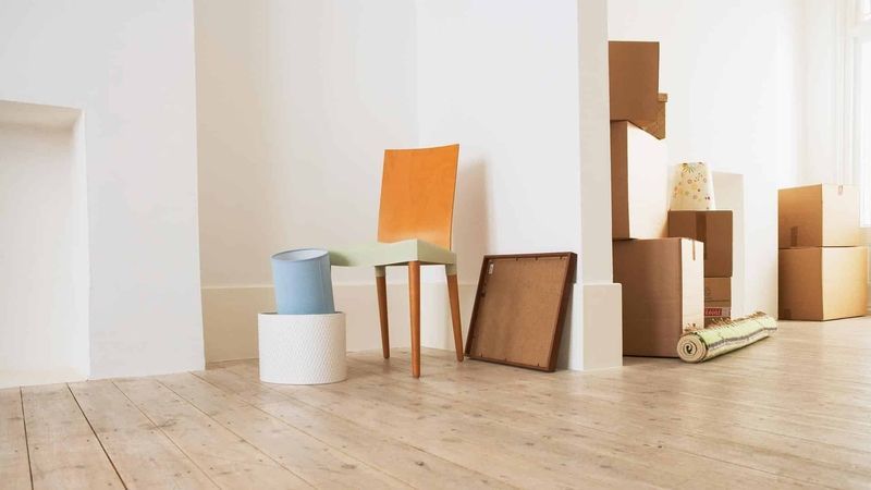 AST-Trans GmbH - Ein Raum mit Holzboden, Stühlen, Kisten und einem Teppich.