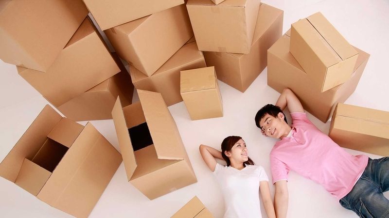 AST-Trans GmbH - Ein Mann und eine Frau liegen umgeben von Pappkartons auf dem Boden.