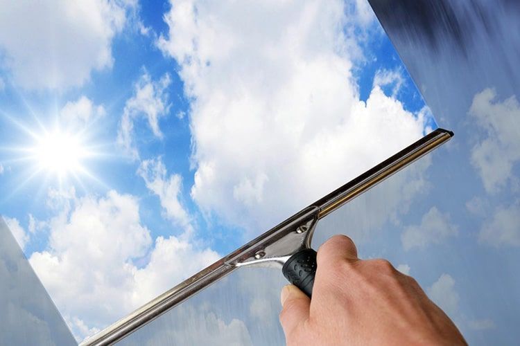 AST-Trans GmbH - Eine Person reinigt ein Fenster mit einem Abzieher.