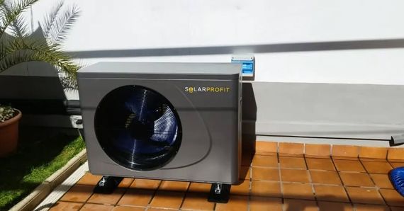 Un ventilador está sentado en un suelo de baldosas al lado de una planta en maceta.