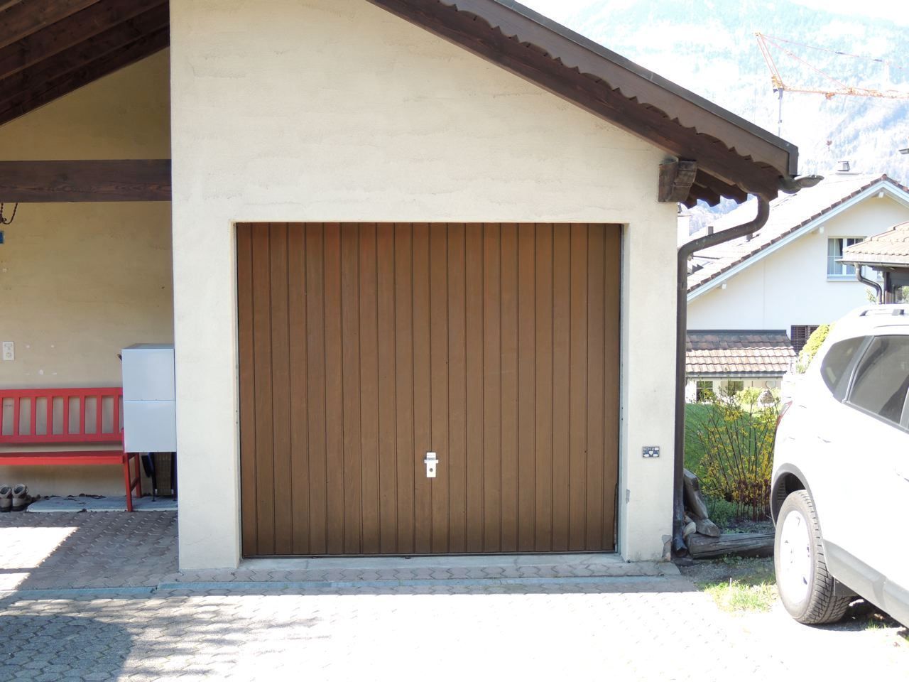 Ein weißes Auto ist vor einem braunen Garagentor geparkt, Malergeschäft Jost