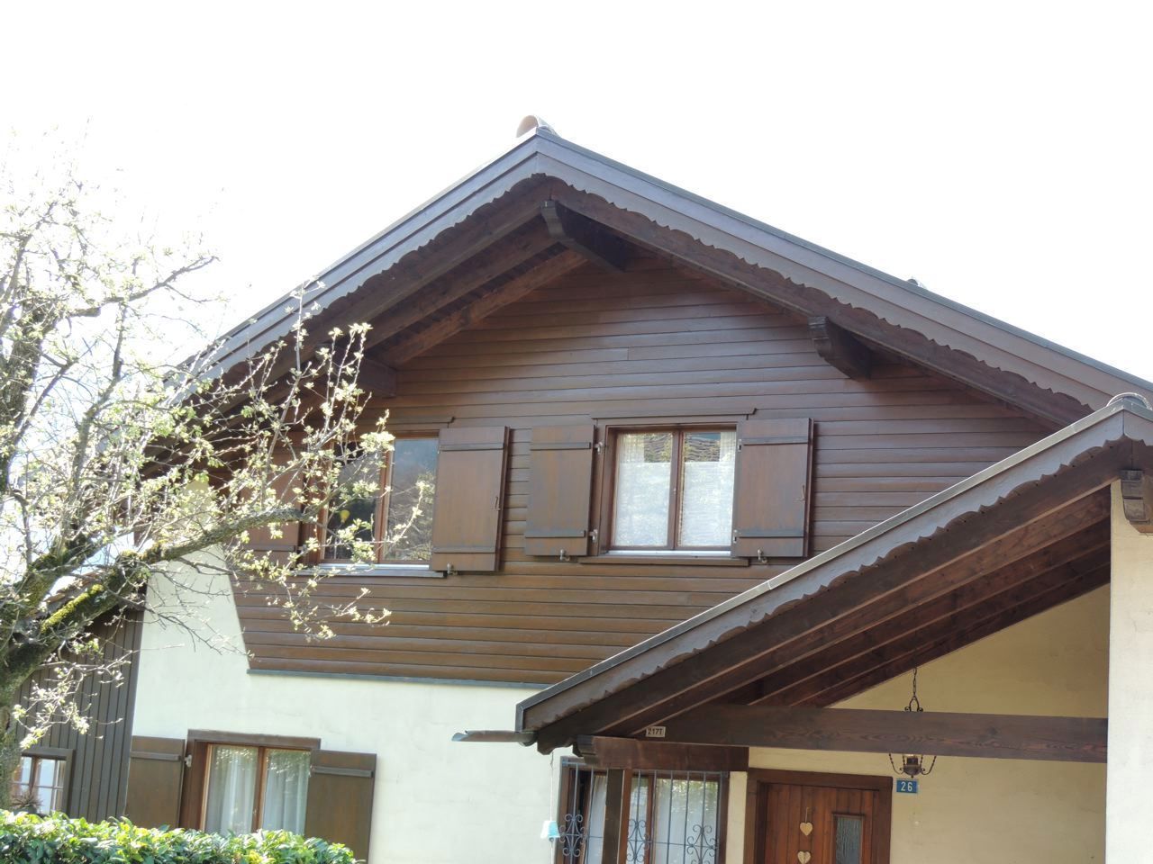 Ein Haus mit einem Holzdach und Fensterläden, Malergeschäft Jost