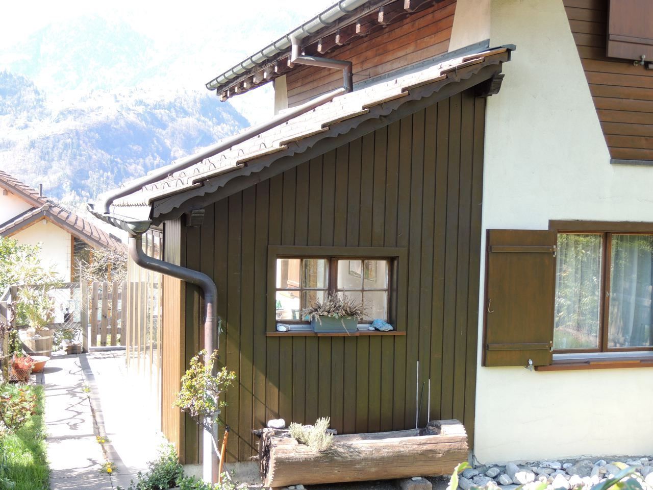 Die Seite eines Hauses mit einem Fenster und einem Abflussrohr, Malergeschäft Jost