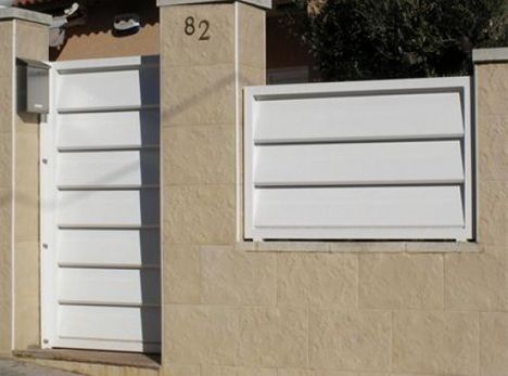 Hay una puerta blanca y una valla blanca delante de la casa.