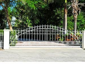 Una puerta corrediza blanca está rodeada de árboles y un camino de entrada.