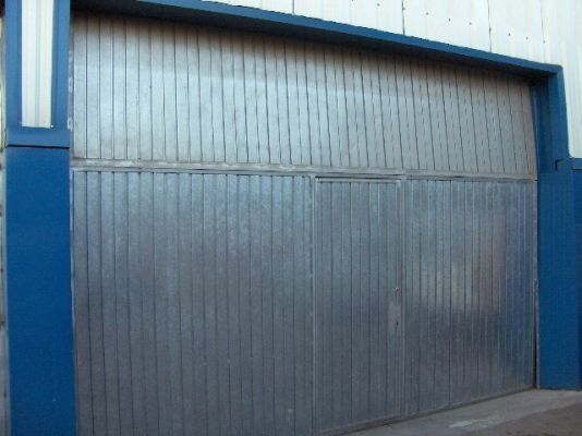 Una gran puerta de garaje de metal con un borde azul en el costado de un edificio.
