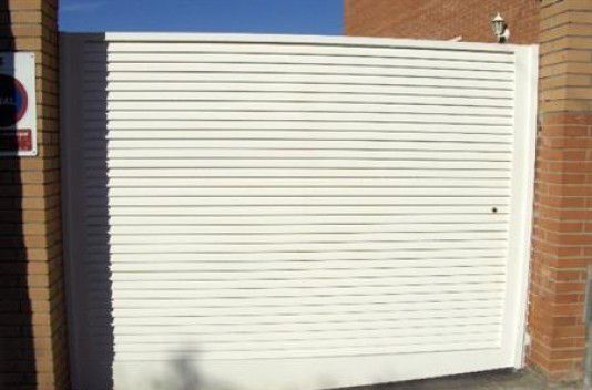 Una puerta de garaje blanca con un cartel de no estacionar al fondo