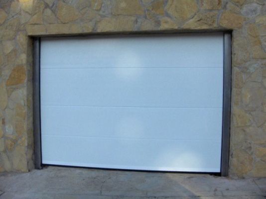 Una puerta de garaje blanca con una pared de piedra detrás.