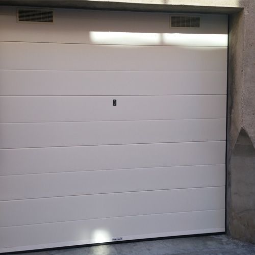 Una puerta de garaje blanca está abierta en un garaje.