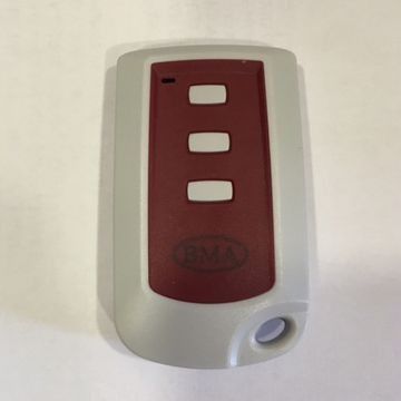 Un control remoto rojo y blanco está sobre una superficie blanca.