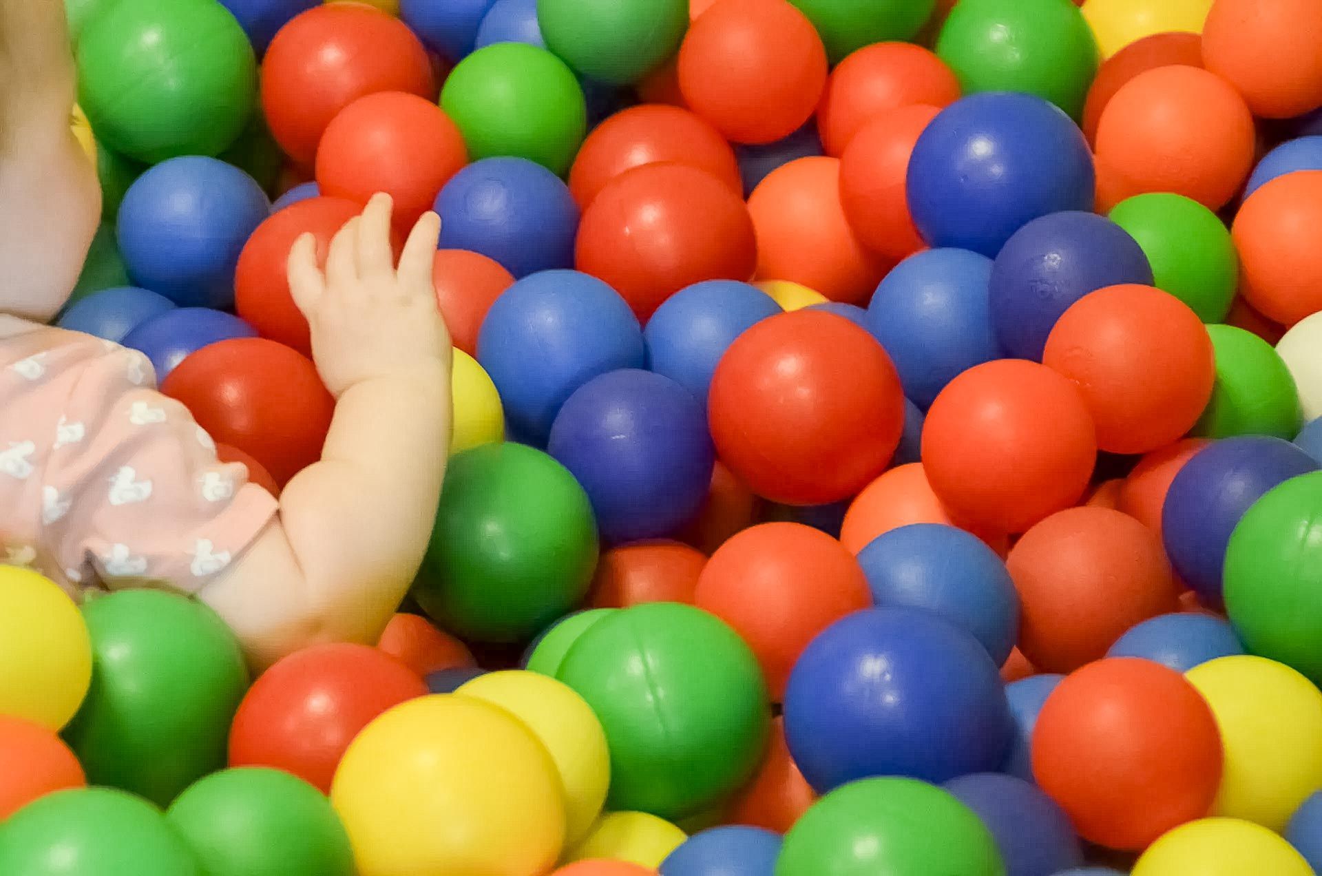 ein Baby spielt in einem Ballbad mit bunten Plastikbällen