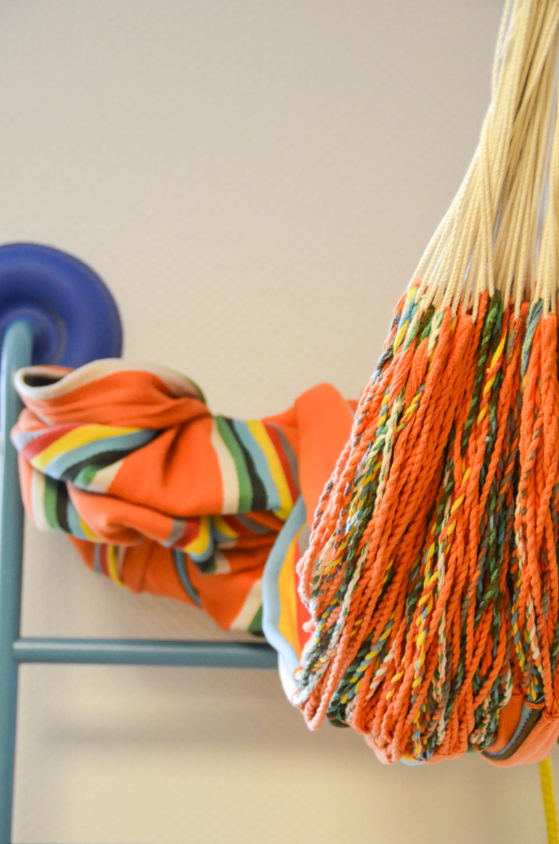 eine bunte Hängematte hängt an einem blauen Stuhl