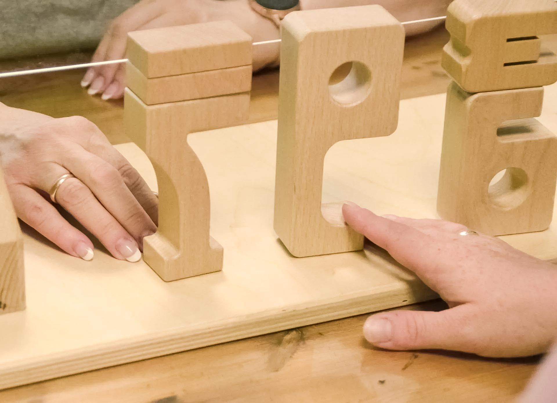 eine Person spielt mit Holzspielzeug mit Buchstaben