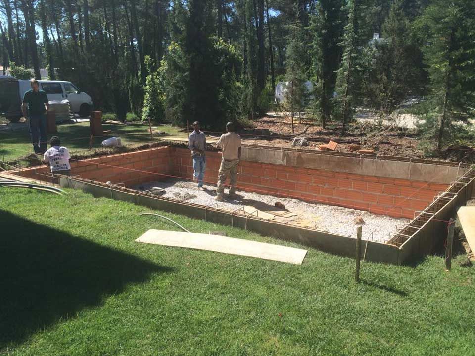 Um grupo de homens está trabalhando em uma piscina no quintal.
