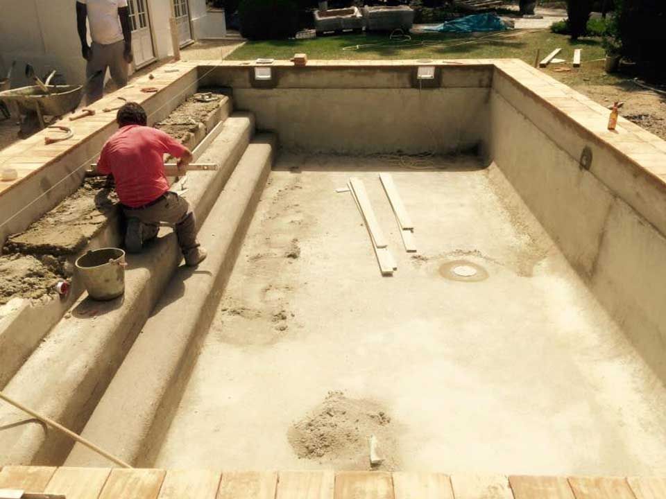 Um homem de camisa vermelha está trabalhando em uma piscina