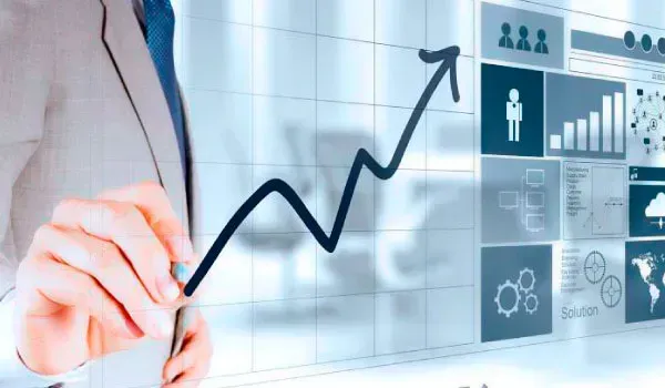 Persona dibujando un gráfico de líneas de tendencia ascendente en una pantalla digital con varias visualizaciones de datos comerciales.