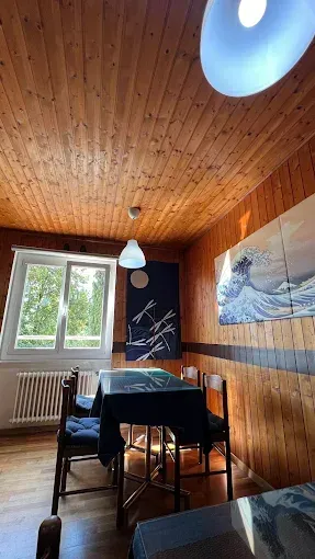 Intérieur du restaurant avec boiseries, tables nappées de nappes foncées, chaises et suspensions lumineuses.