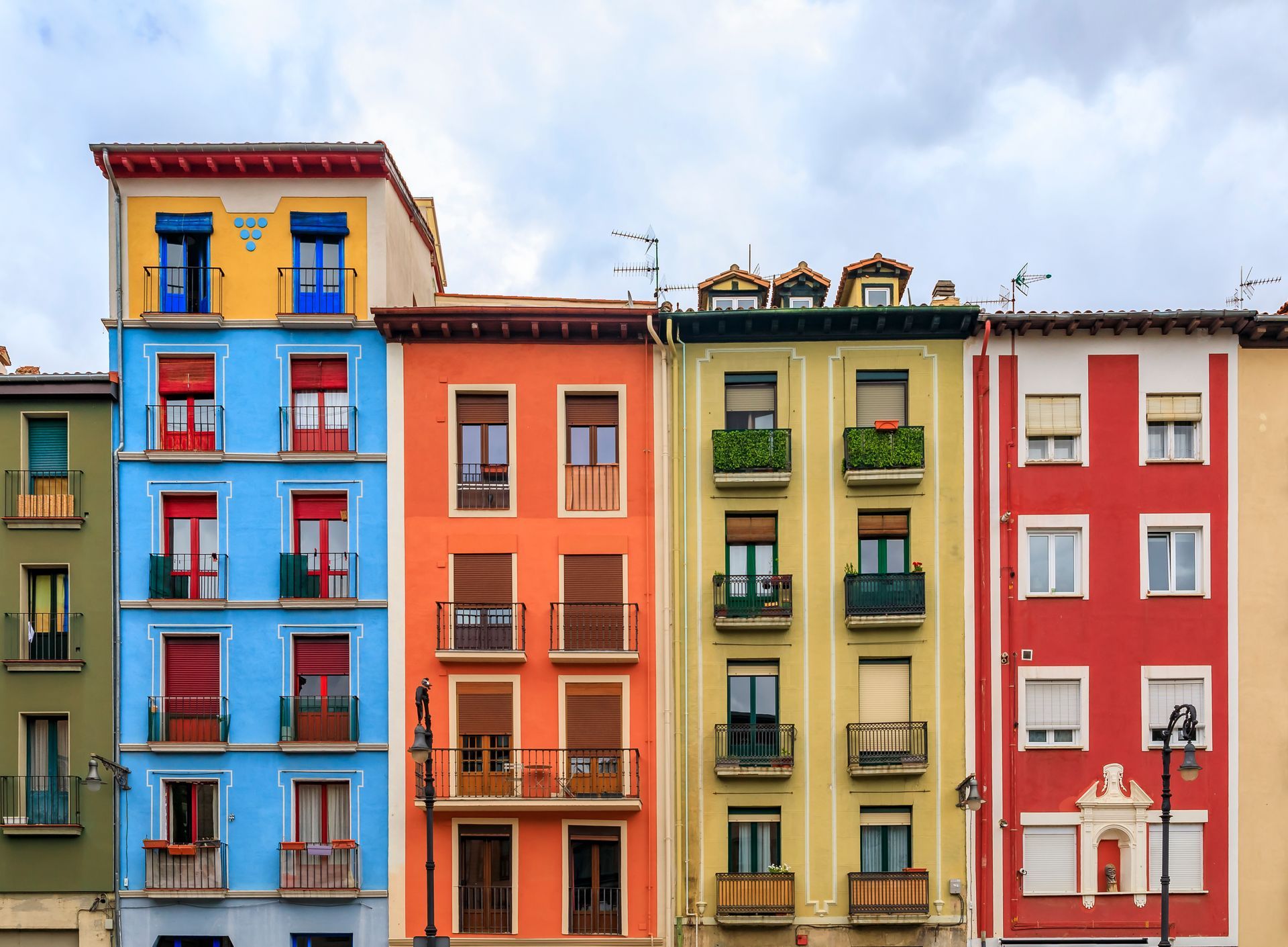Edificios coloridos en fila, incluidas fachadas verdes, azules, naranjas, amarillas y rojas.