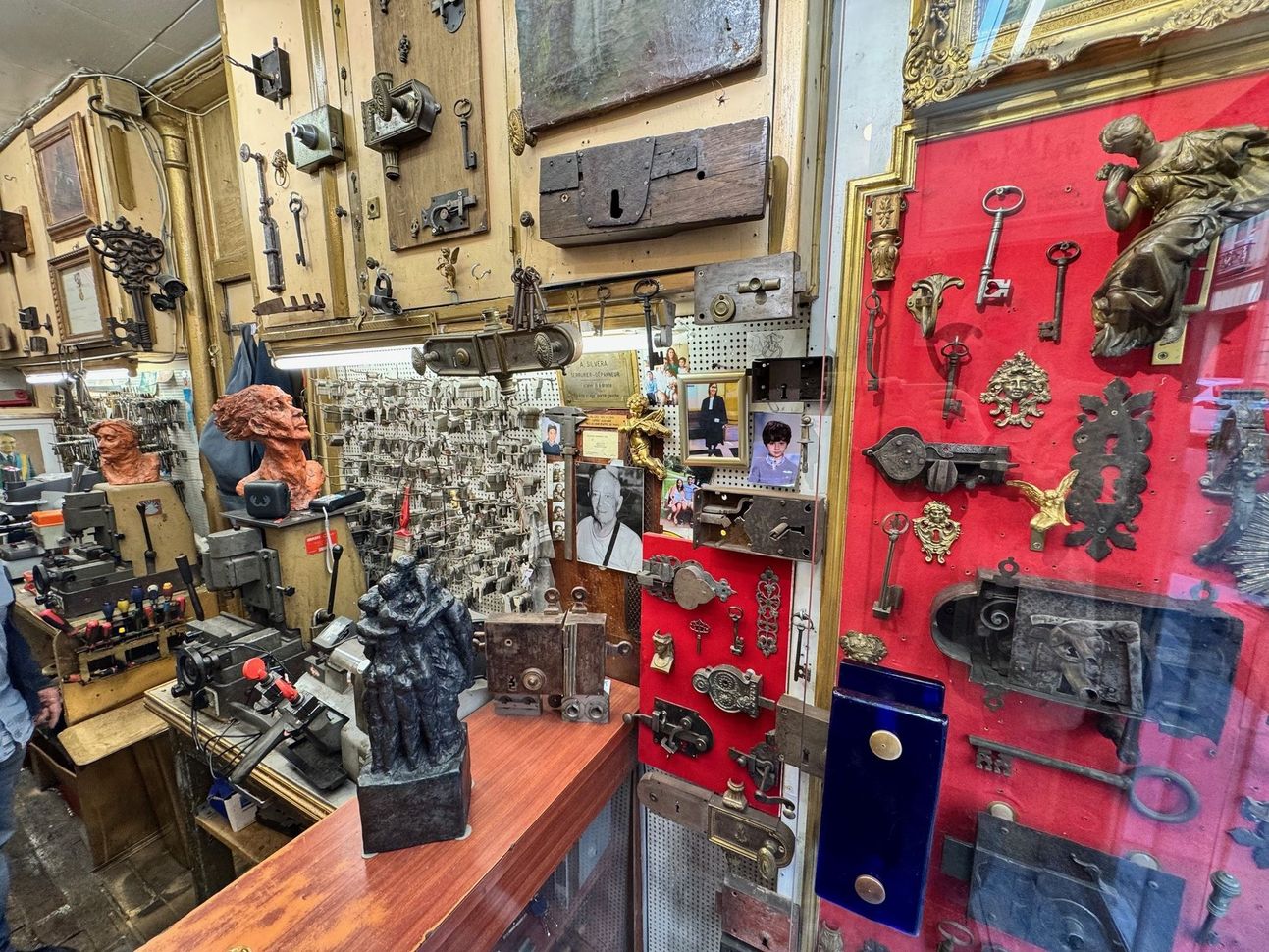 L'intérieur d'un magasin d'antiquités dont les murs sont recouverts de serrures, de clés et de quincaillerie anciennes, y compris un panneau d'affichage rouge.