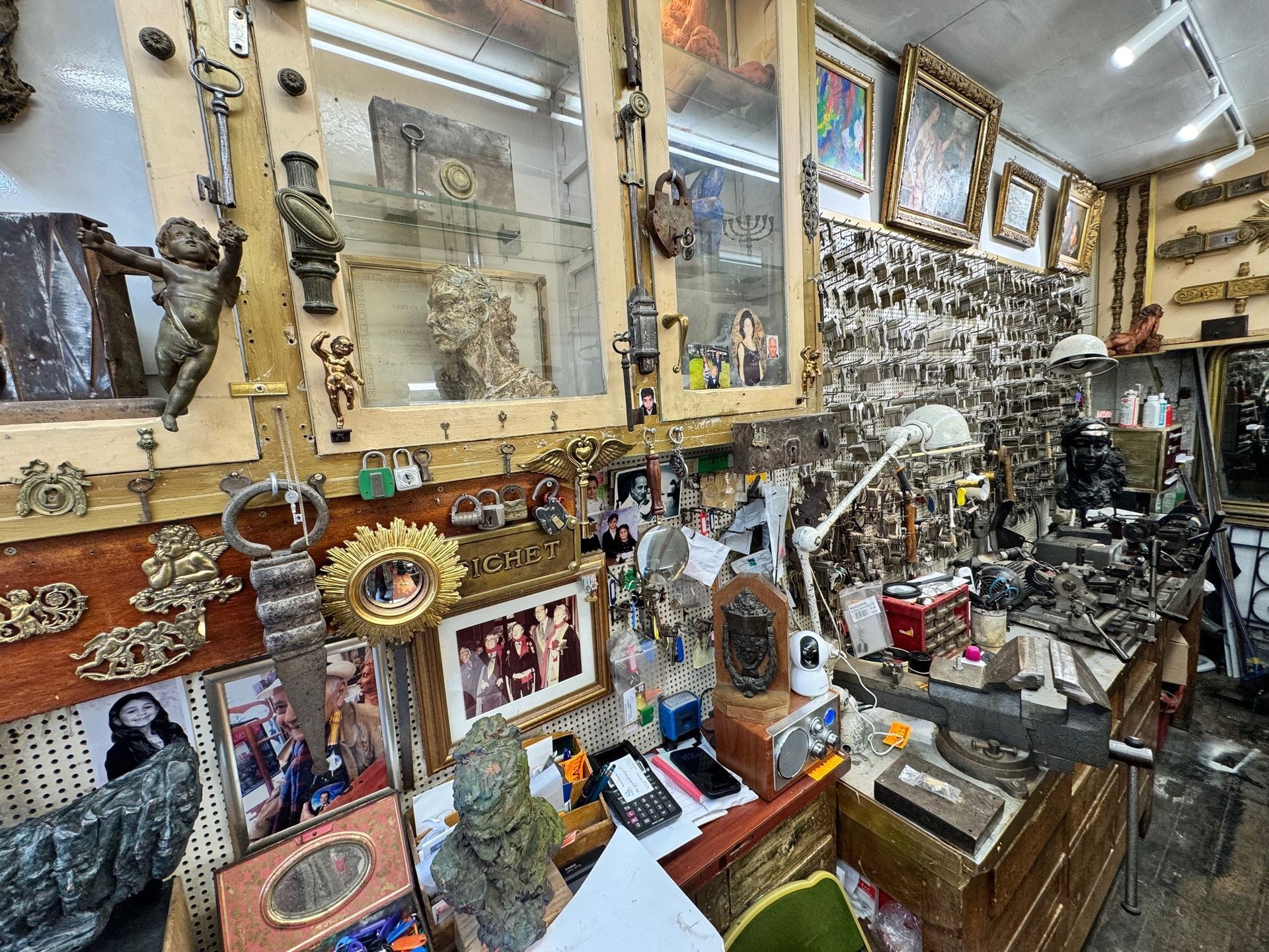 Une boutique d'antiquités encombrée d'horloges ouvragées, de quincaillerie en métal, de sculptures et de photos encadrées exposées sur des étagères et des murs.