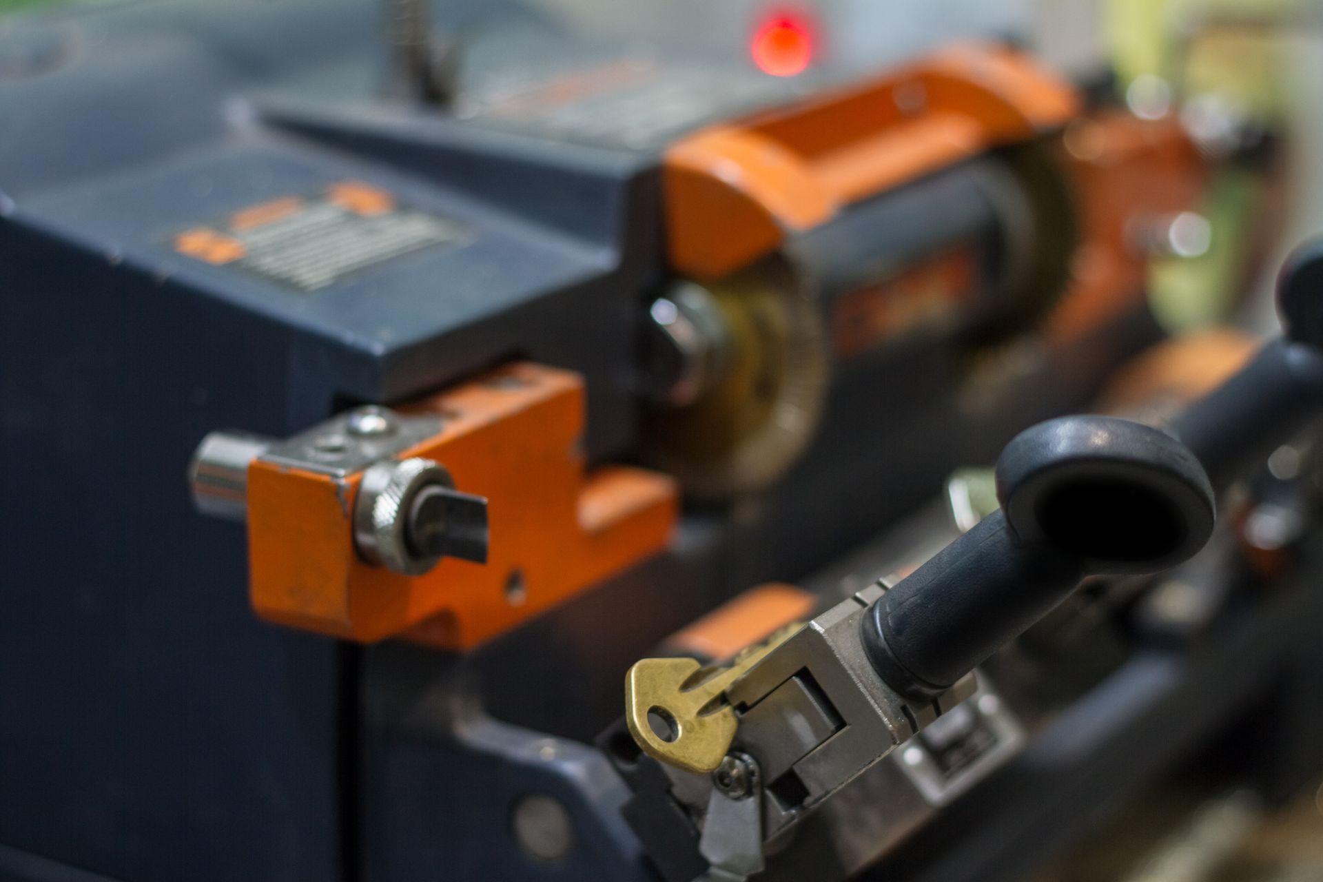 Gros plan sur une machine à dupliquer les clés en métal, avec une clé fixée dans l'étau, positionnée pour être coupée par la lame.