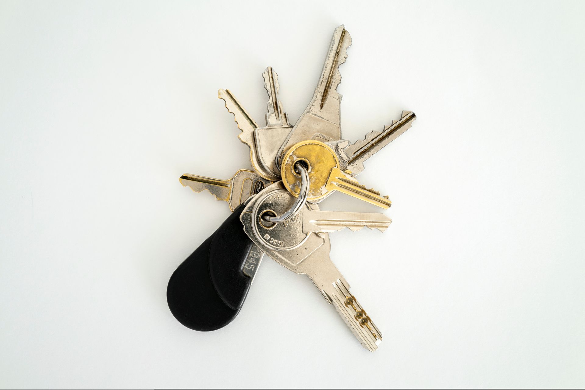Un petit porte-clés en métal retenant plusieurs clés de formes et de tailles variées sur un fond blanc uni.