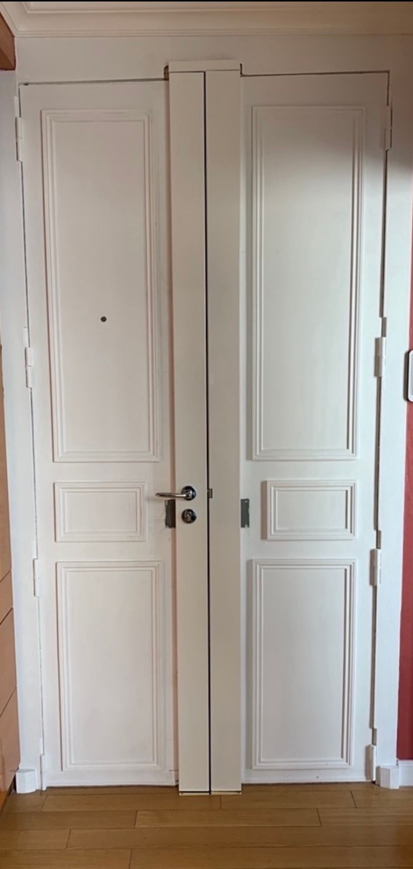 Une personne utilise une perceuse électrique jaune et noire pour installer une plaque de verrouillage métallique sur le bord d'une porte blanche.