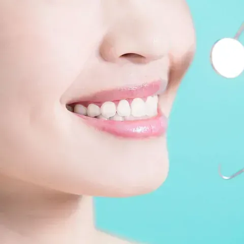 Una mujer sonríe mientras se mira los dientes en un espejo.