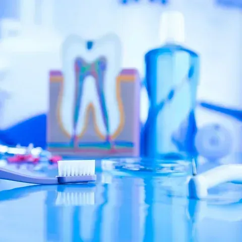 Un cepillo de dientes está sobre una mesa al lado de un modelo de un diente.