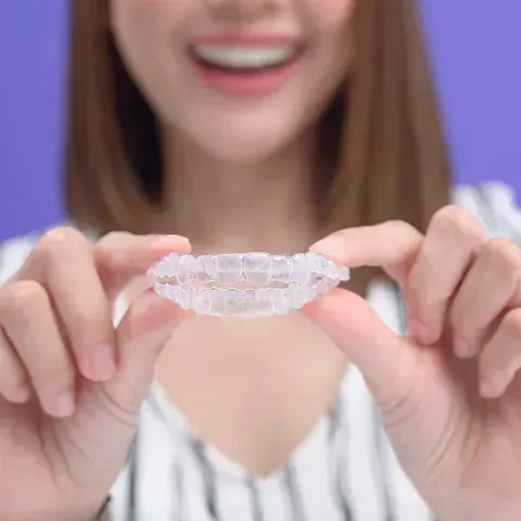 Una mujer sostiene un aparato ortopédico transparente en sus manos.