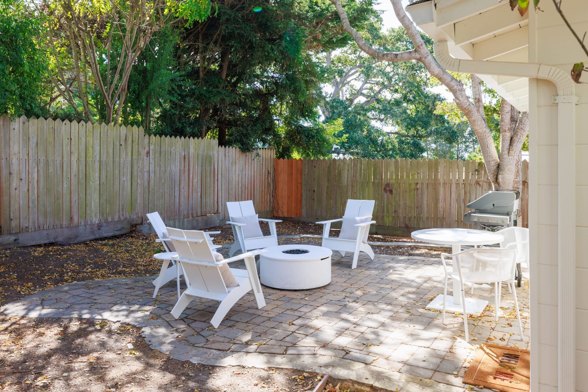 There is a fire pit in the backyard with chairs and tables.