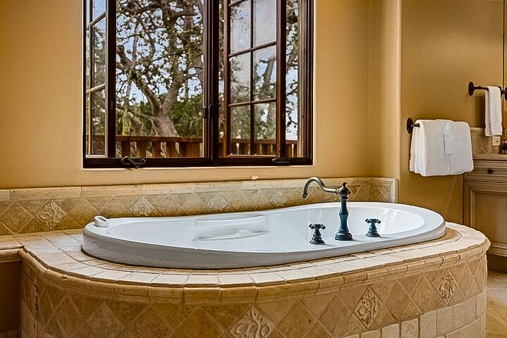 A bathroom with a large bathtub and a window.