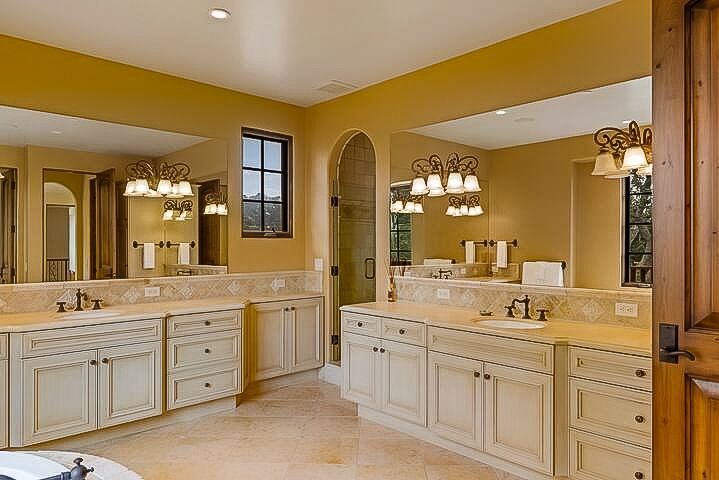 A bathroom with two sinks , two mirrors and a tub.