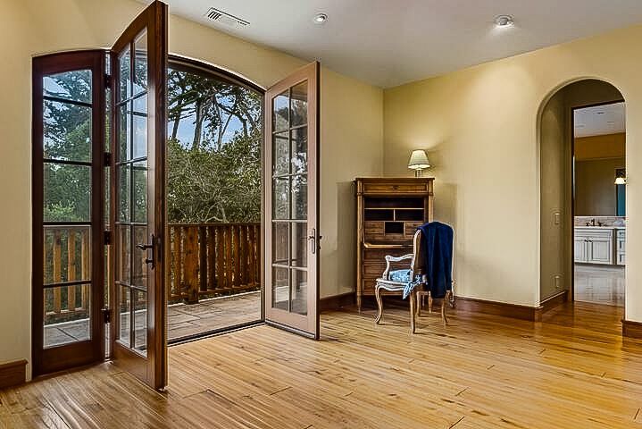 An empty living room with hardwood floors and french doors leading to a patio.