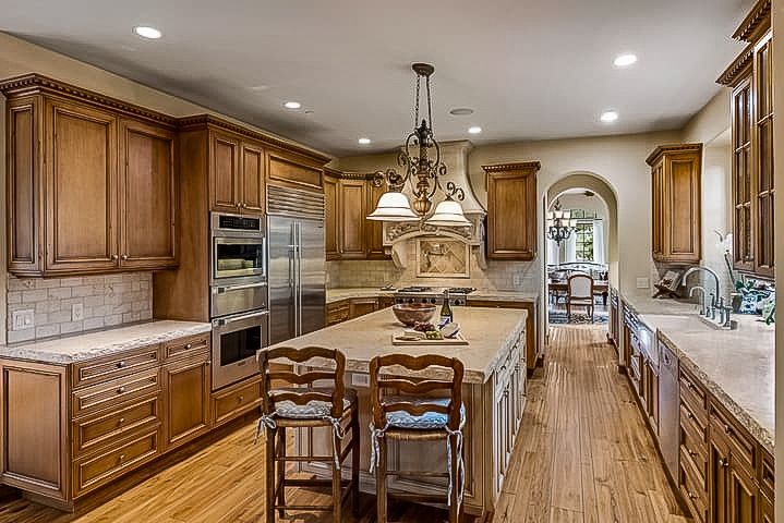 A kitchen with wooden cabinets , stainless steel appliances , and a large island.