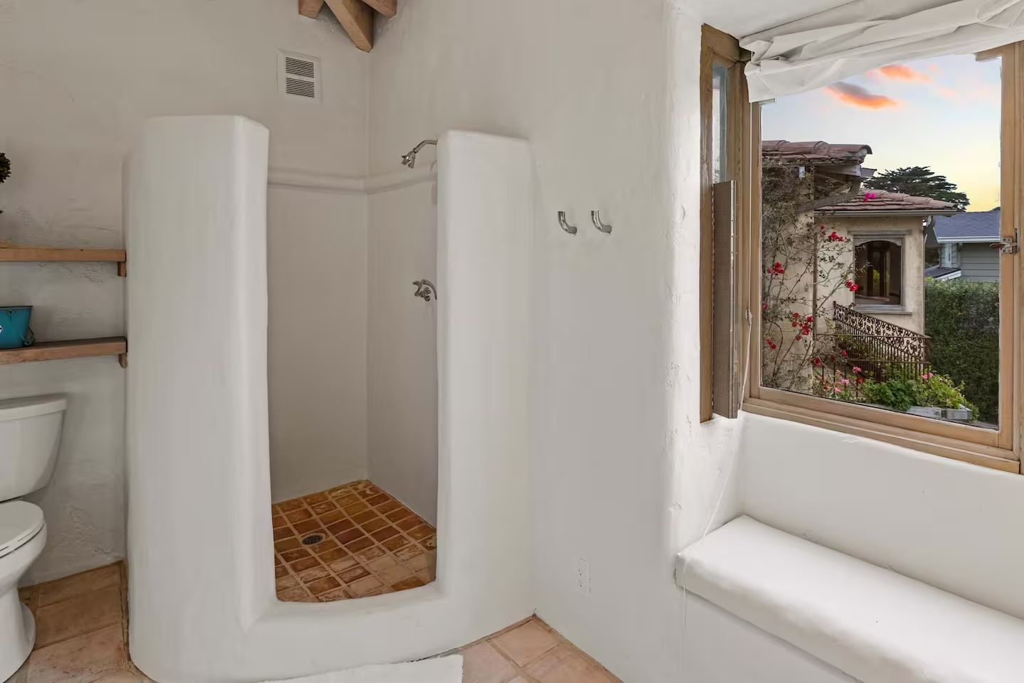 A bathroom with a toilet , shower and window.