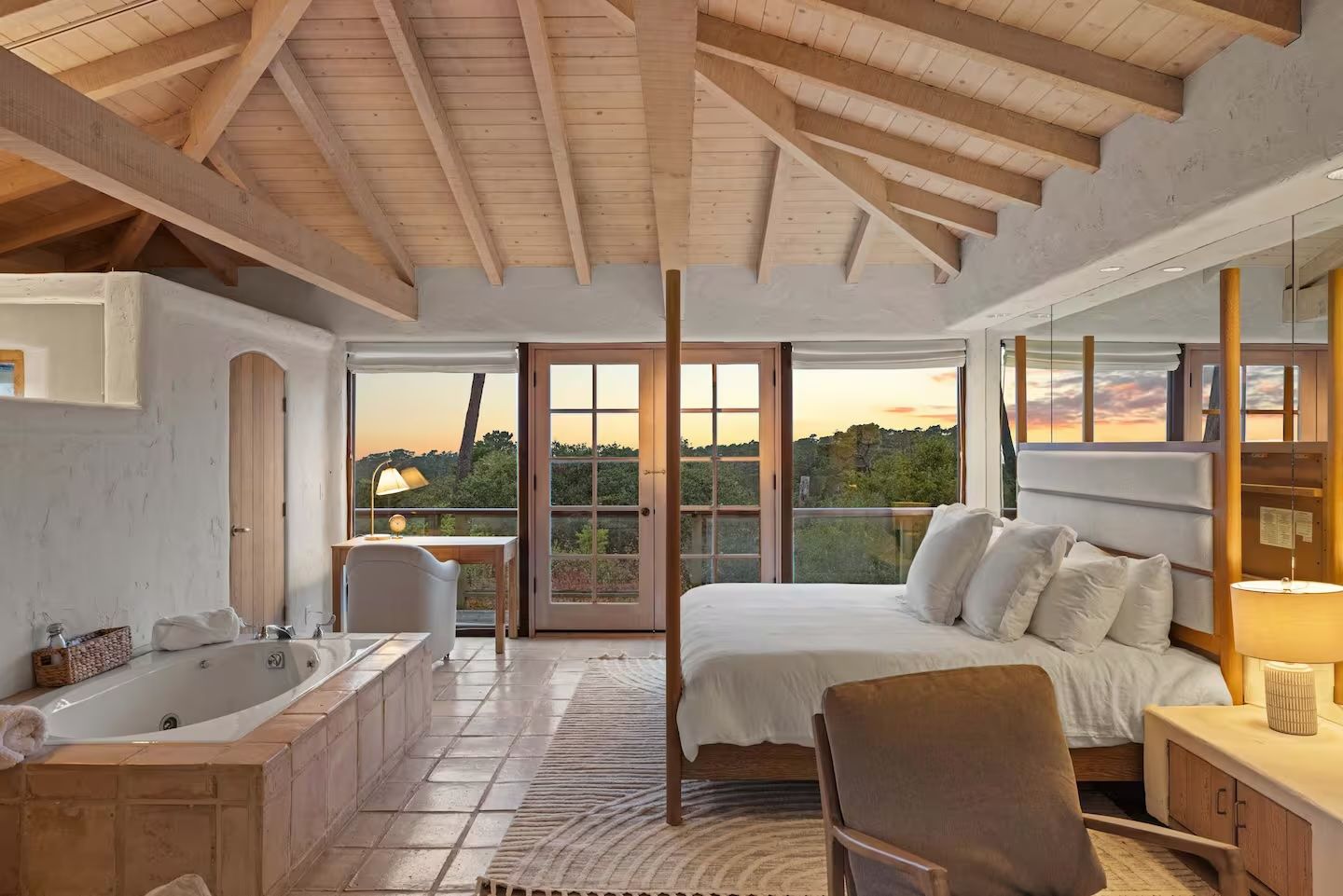 There is a large bedroom with a large bed and a bathtub.