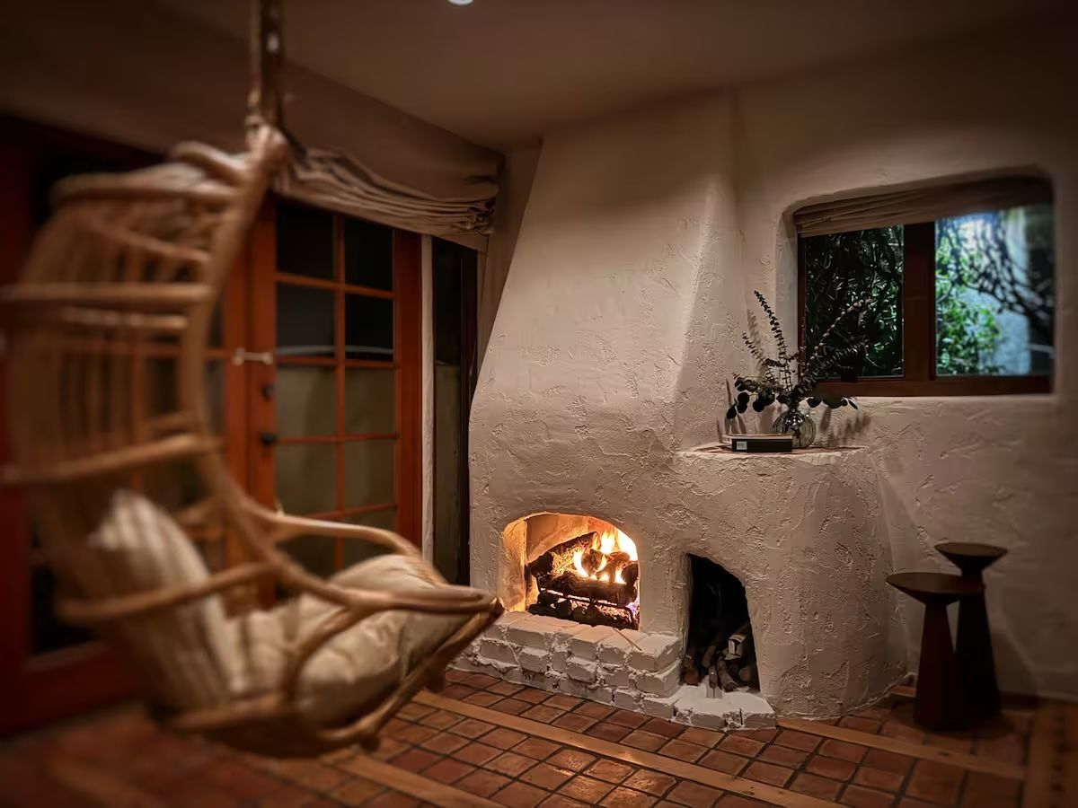A living room with a fireplace and a wicker chair.
