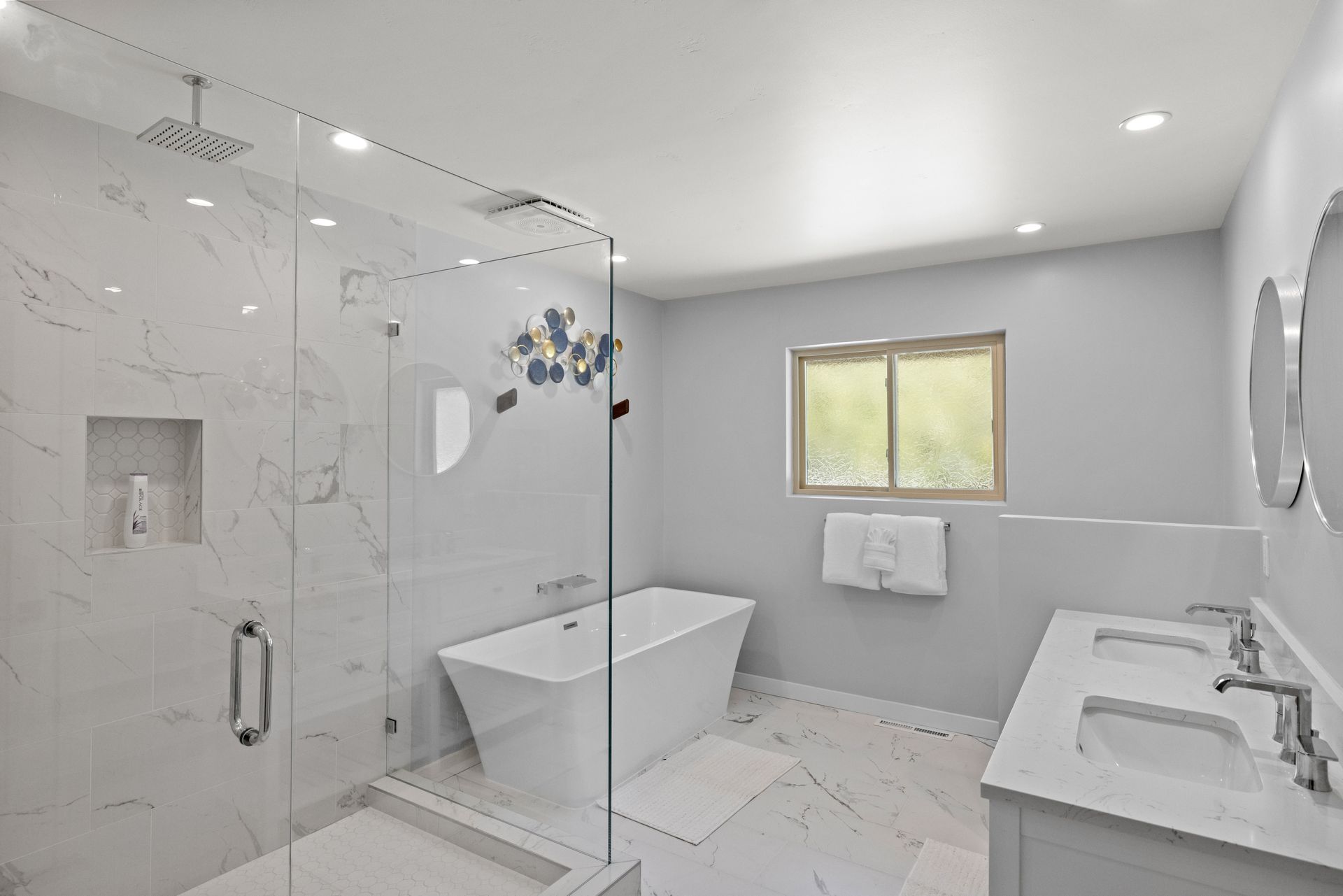 A bathroom with a tub , sinks , and a walk in shower.