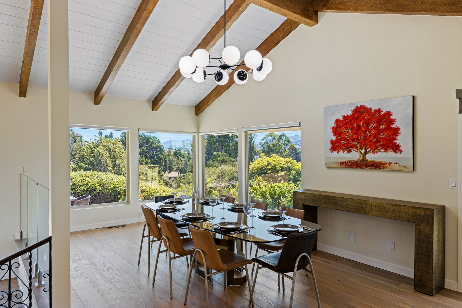 A large dining room with a table and chairs and a painting of a tree on the wall.