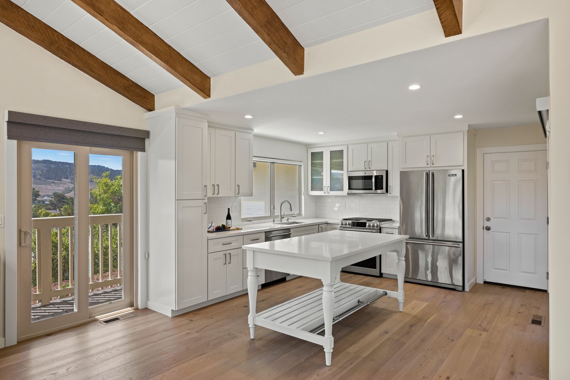 A kitchen with white cabinets , stainless steel appliances and a large island.