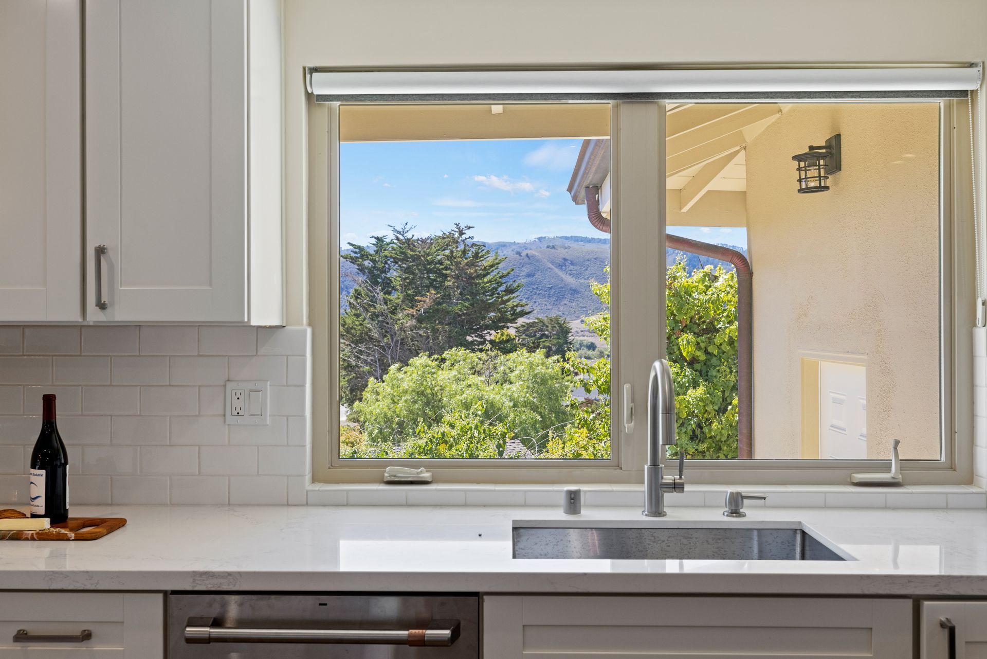 A kitchen with a sink and a window with a view of trees.