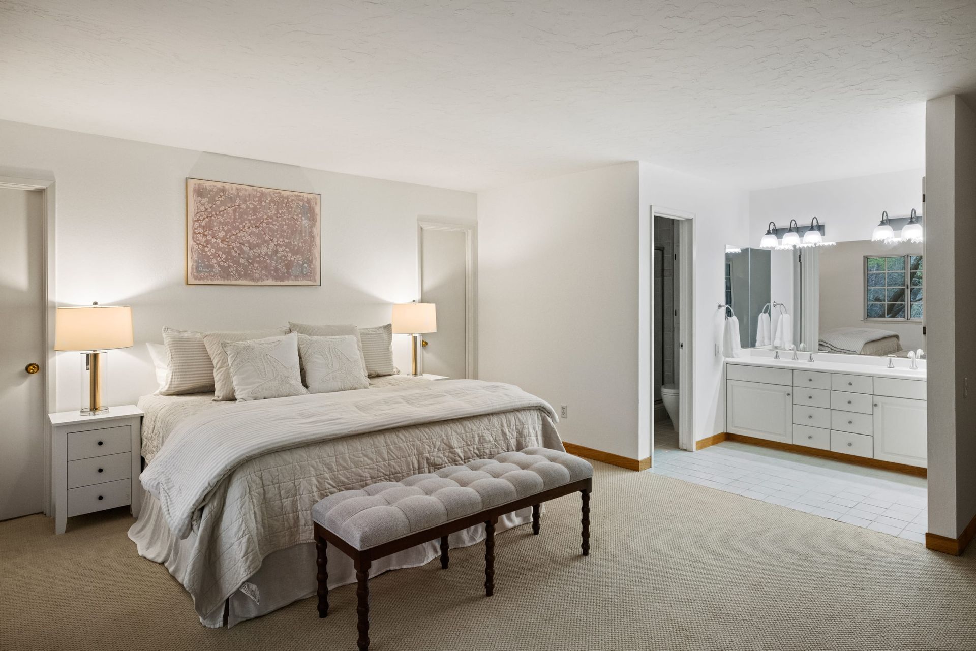 A bedroom with a king size bed and a bench.