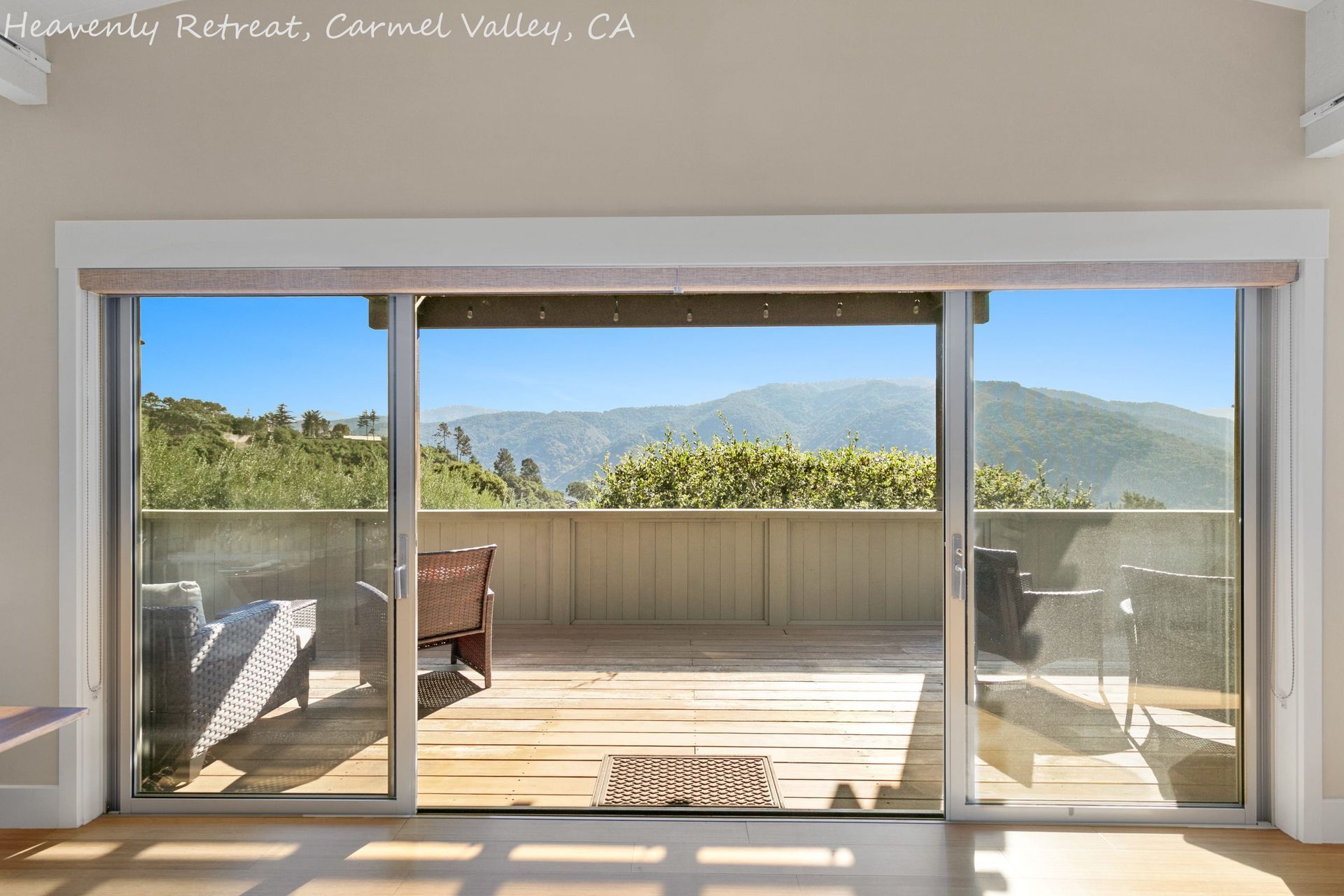 A sliding glass door opens to a deck with mountains in the background