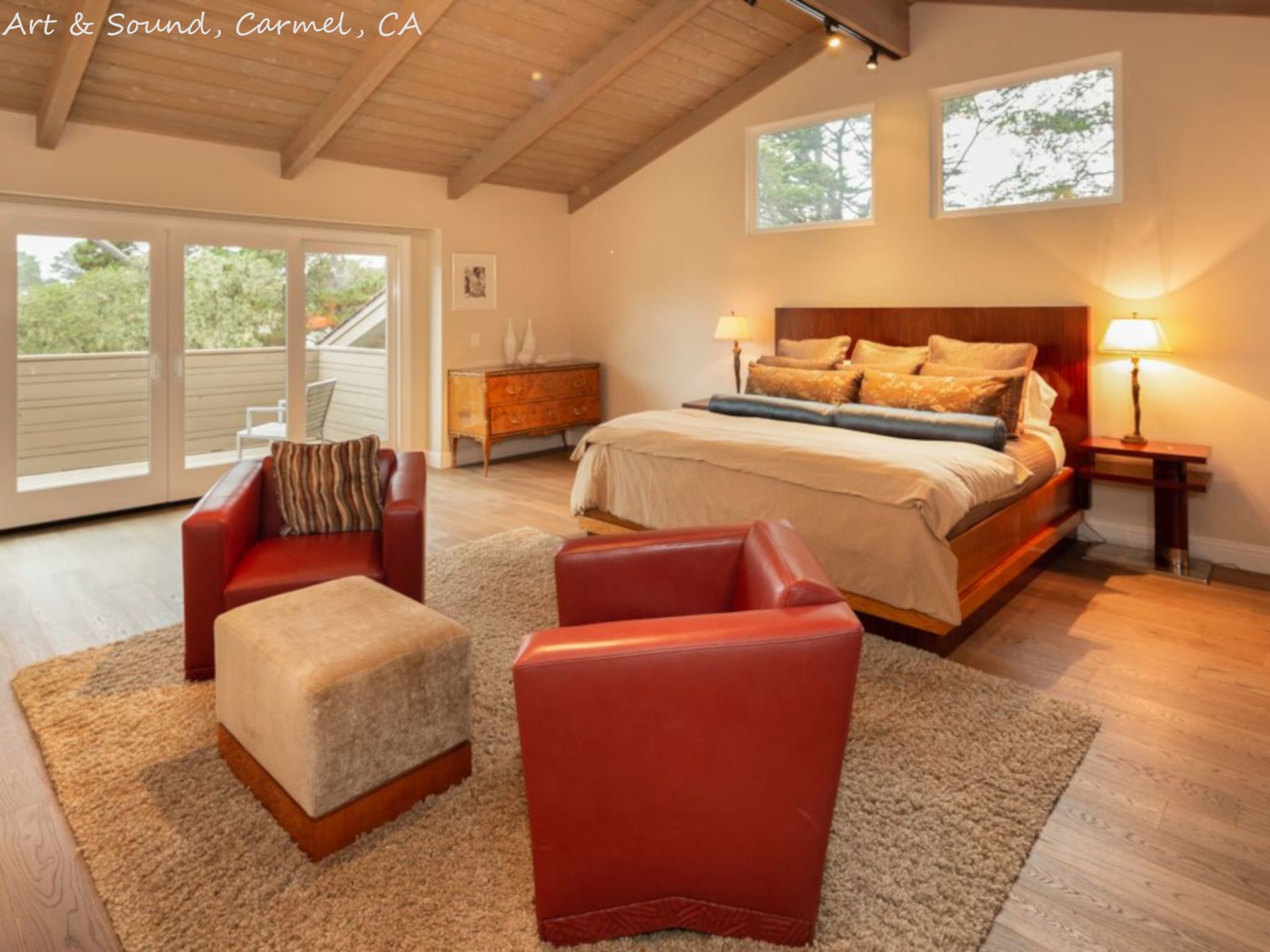 A bedroom with a large bed and two red chairs