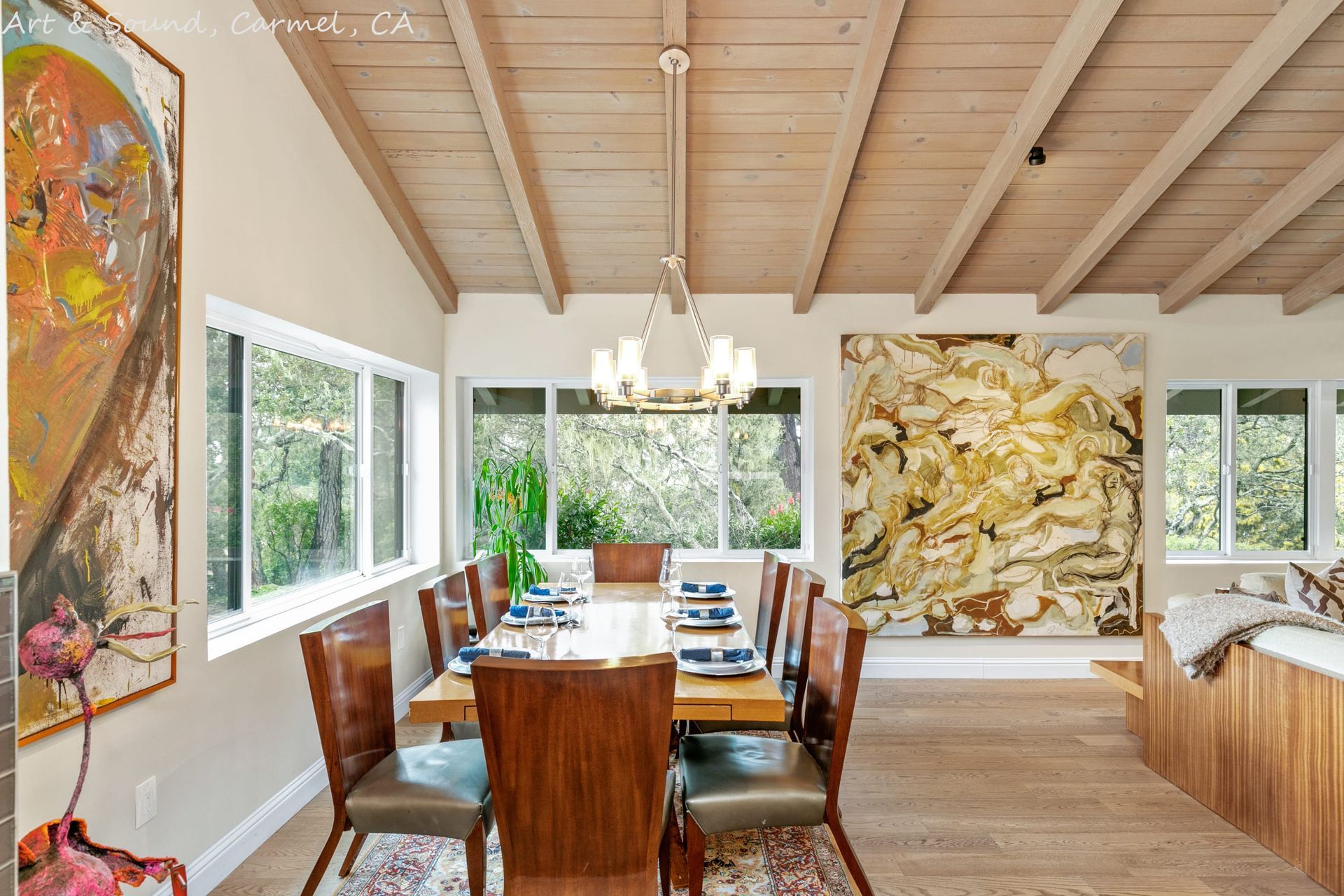 A dining room with a table and chairs and a large painting on the wall.