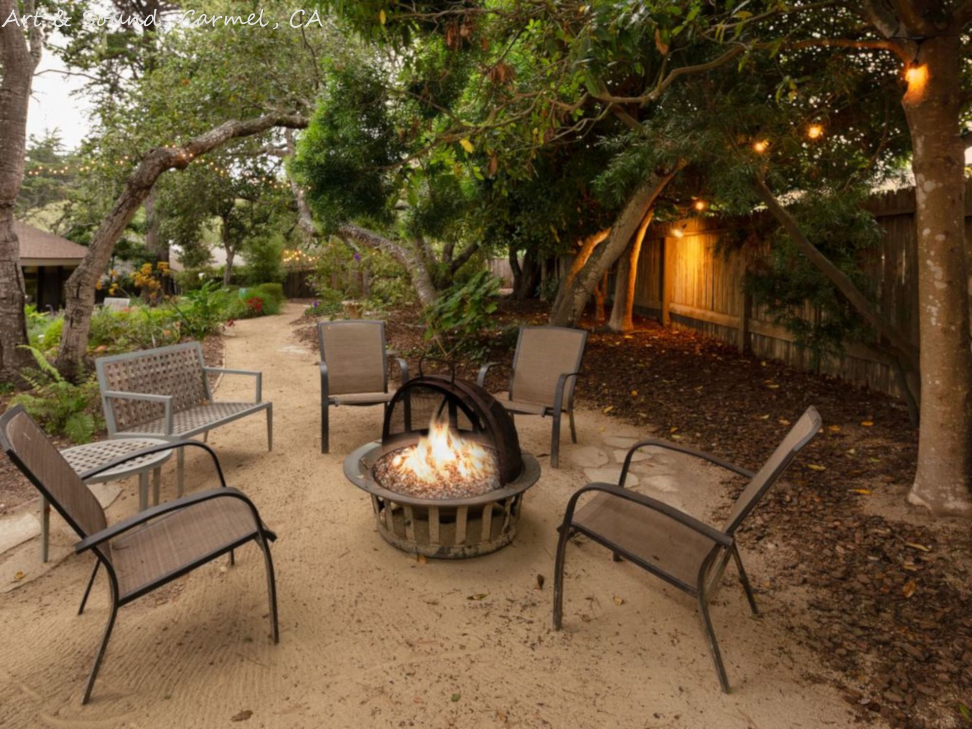 A fire pit is surrounded by chairs and a bench