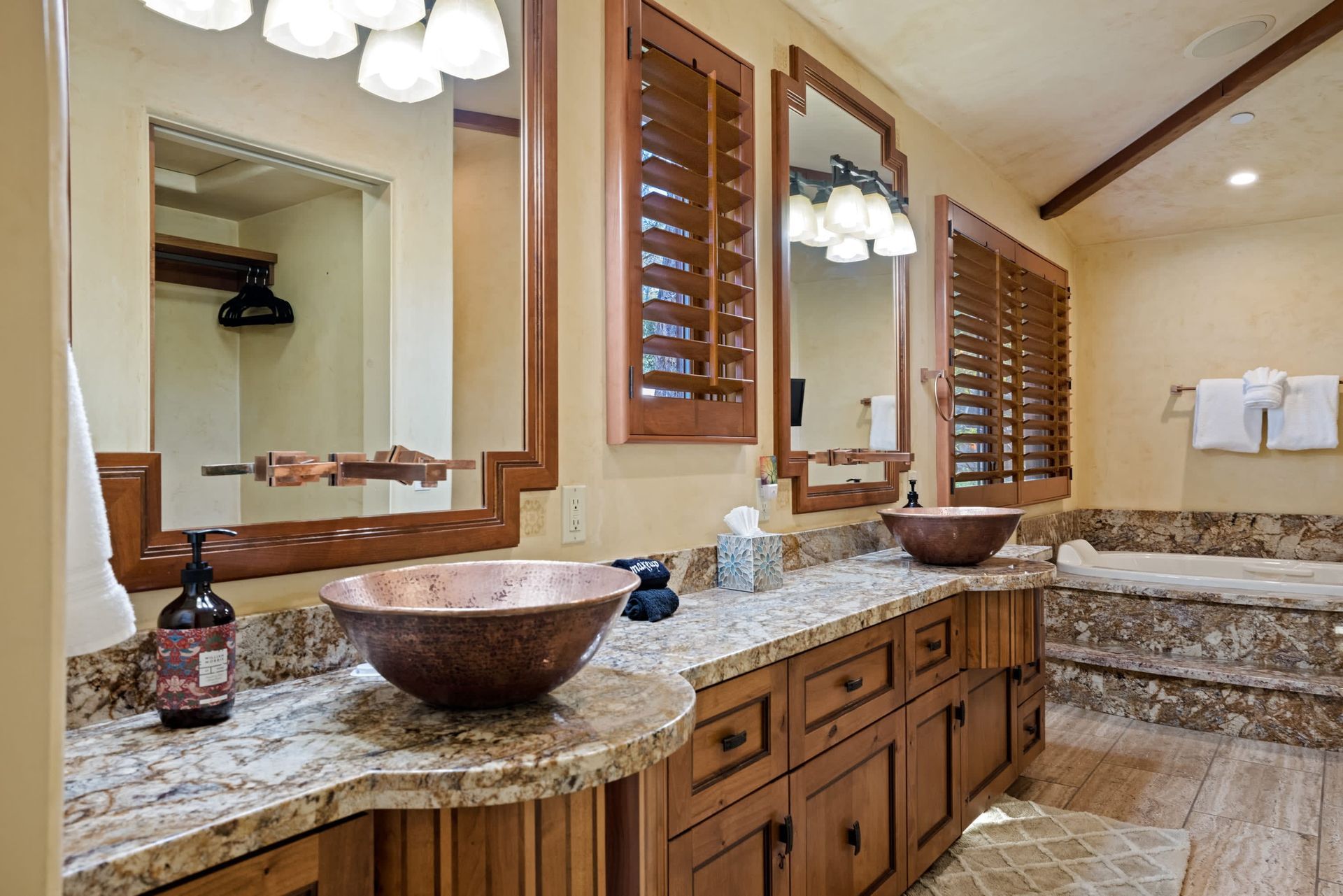 A bathroom with two sinks , two mirrors and a tub.