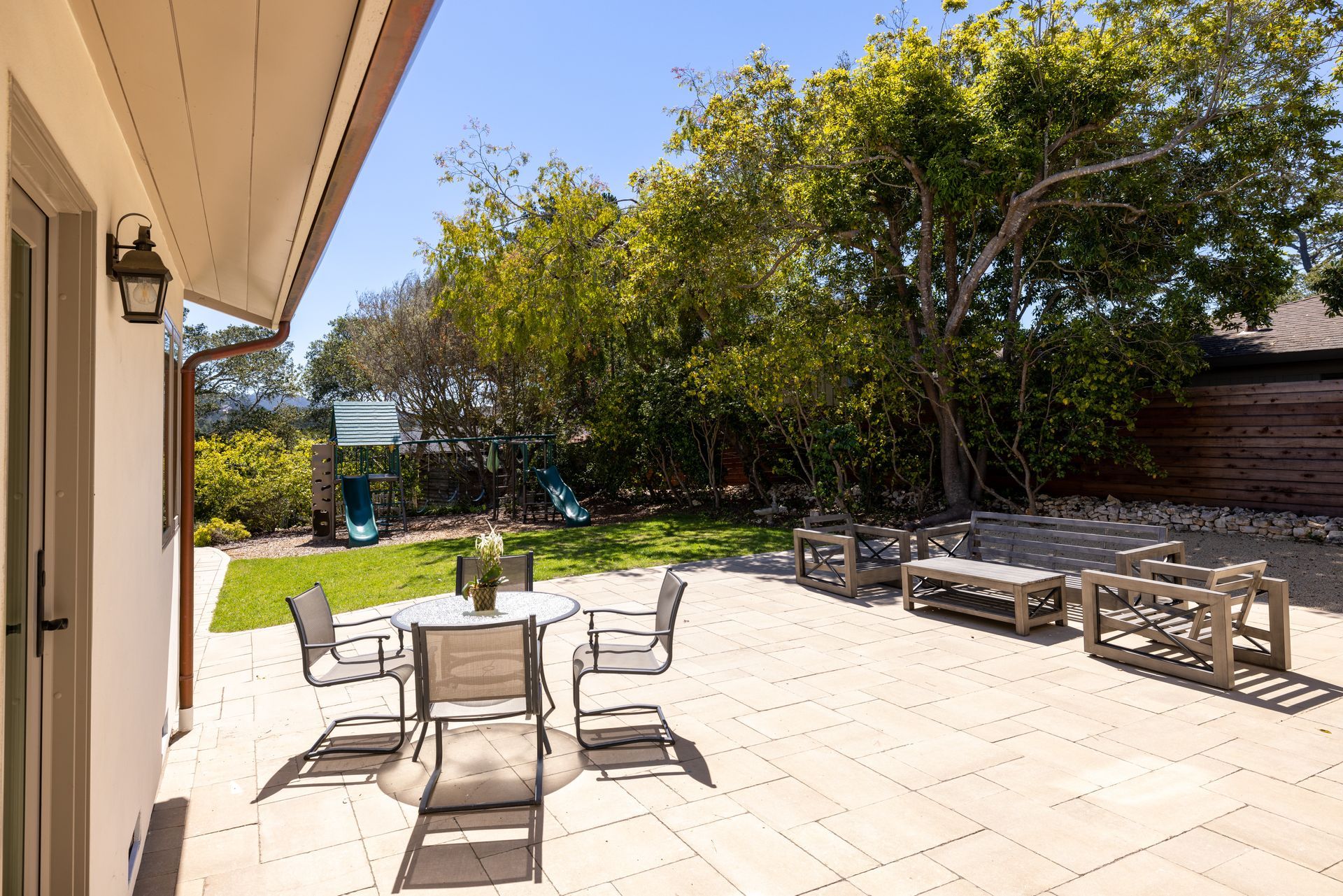 A patio with a table and chairs in the backyard of a house.