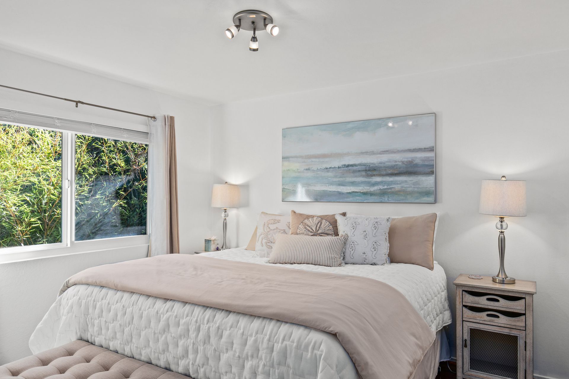 A bedroom with a bed , nightstand , lamps and a painting on the wall.